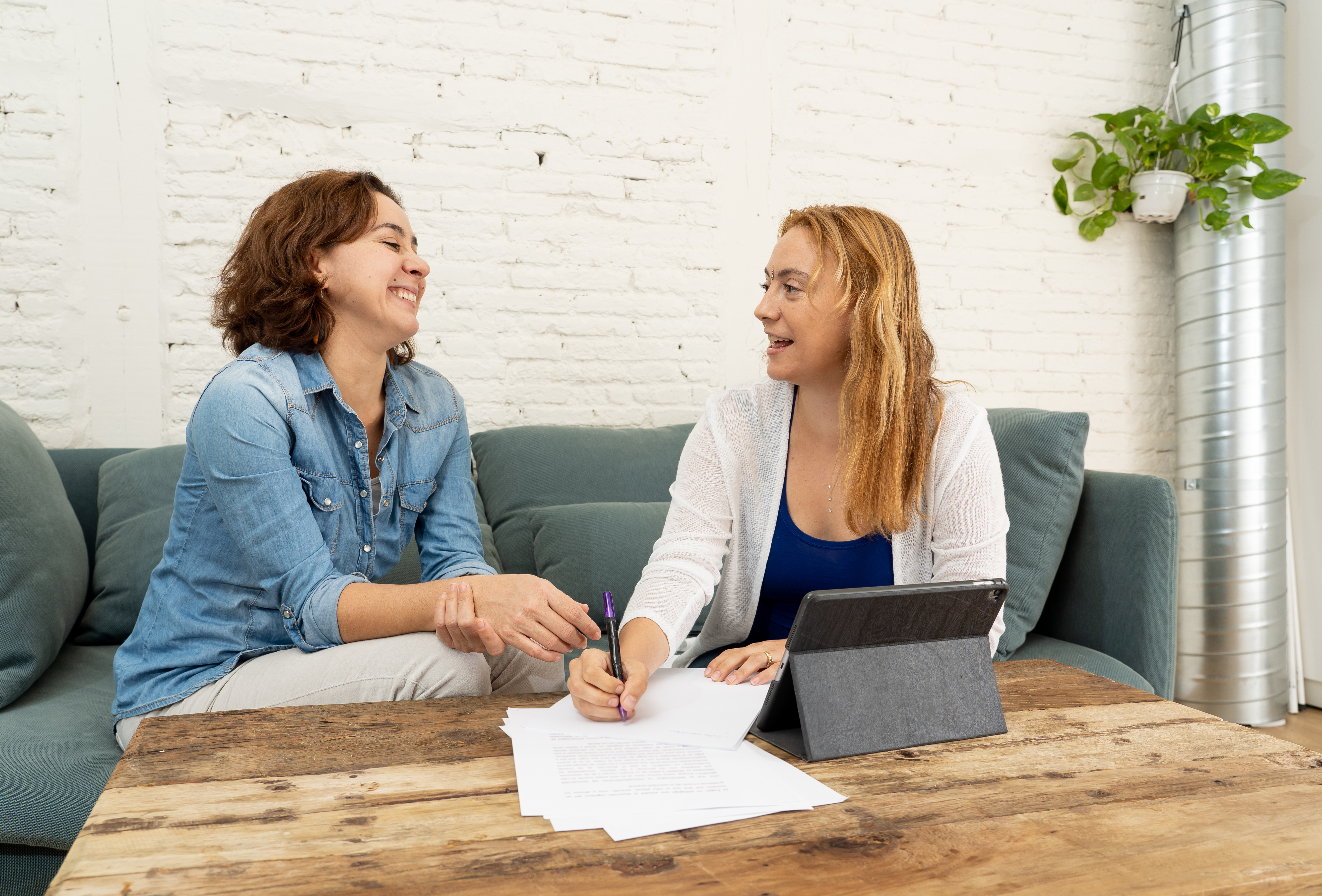 A photograph of two women talking while sitting on a couch