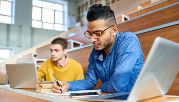 A photograph of two students in a lecture hall studying