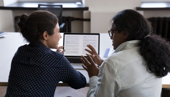 faculty member and student talking and viewing laptop screen