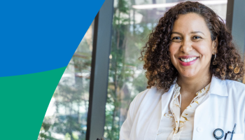 Person in a white lab coat standing indoors near windows, with greenery outside and blue‑green graphic elements.
