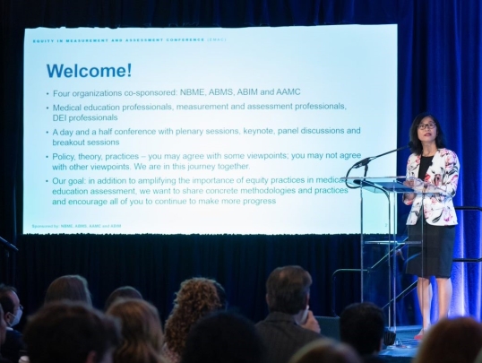 woman standing in from of conference welcome slide