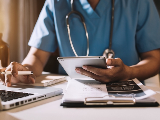 doctor sitting at desk holding a tablet