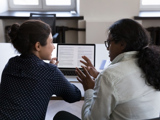 faculty member and student talking and viewing laptop screen