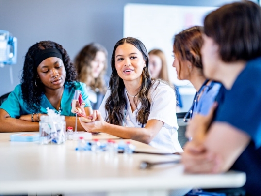 four medical students sitting at a table studying 