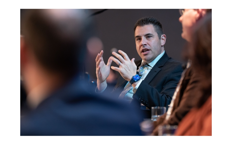 man speaking on stage during conference panel