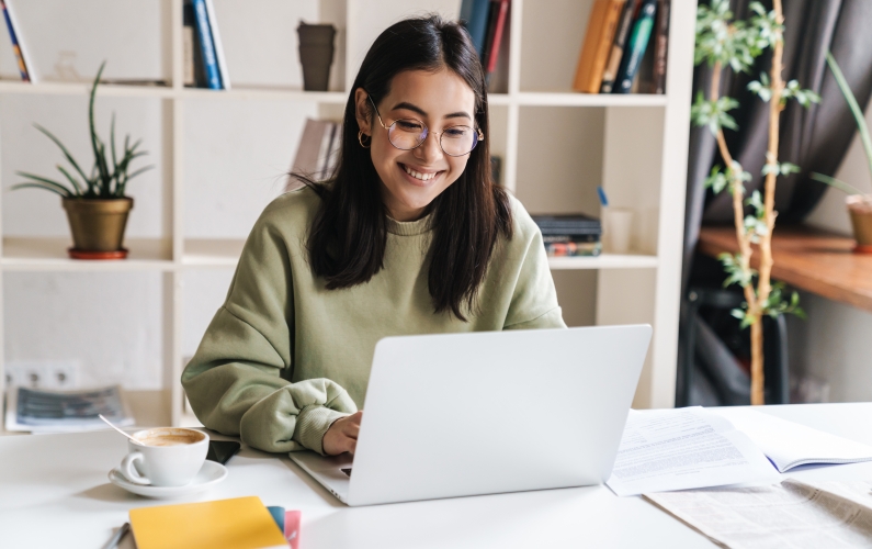 student smiling and working on a laptop
