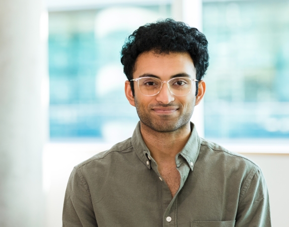 student with dark hair and glasses smiling at camera