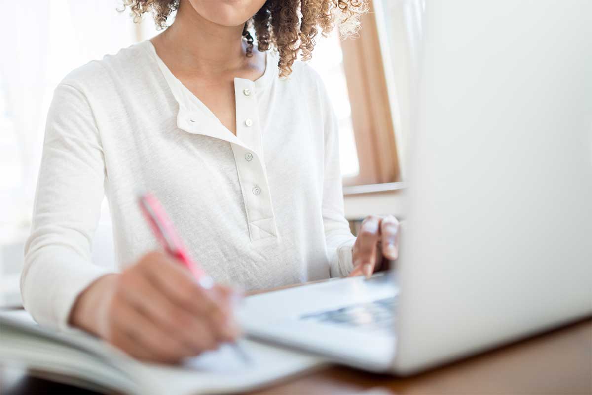 Student taking notes with a laptop
